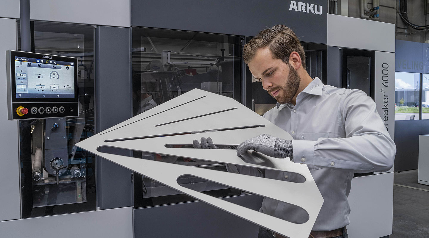 Mensch mit großem Laserteil vor Entgratmaschine