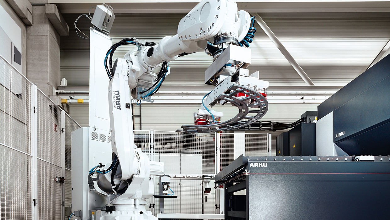 Handling robot lifts part onto conveyor belt of leveling machine
