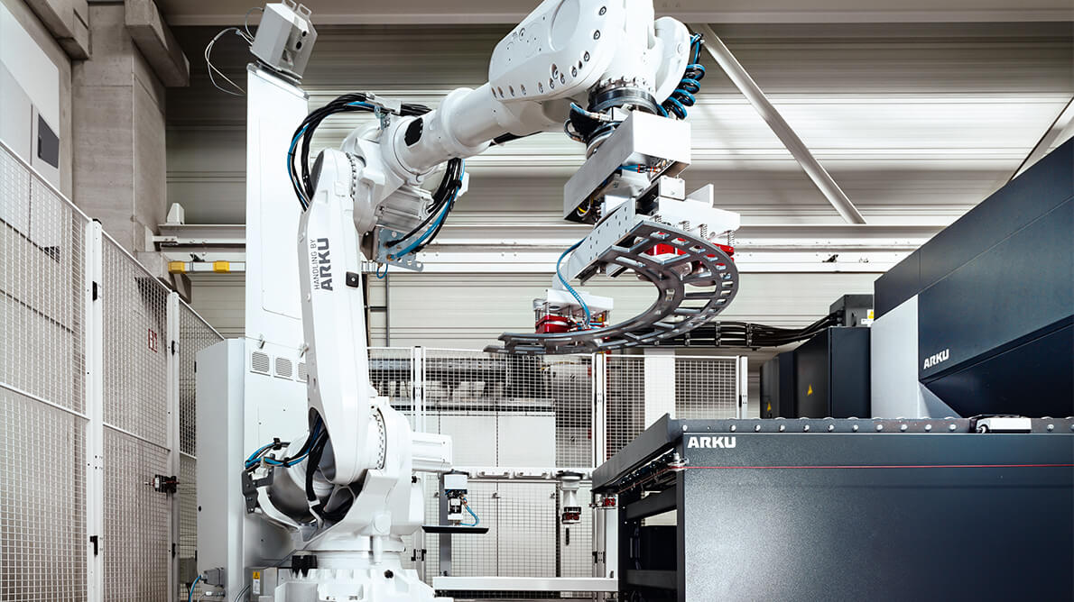 Robot obsługujący ARKU przenosi detal na taśmę podawczą maszyny prostującej 